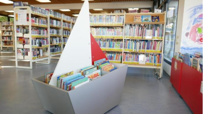 Ein Büchertrog mit der Form eines Schiffs gefüllt mit Bilderbüchern