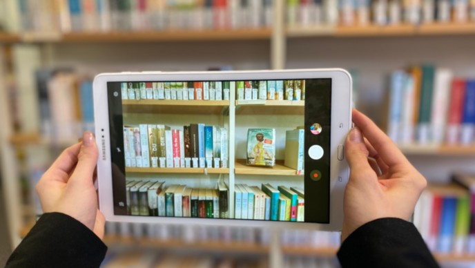 Ein Tablet mit dem Romane in einem Regal fotografiert werden