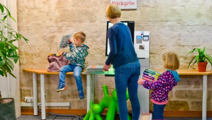Anmeldung und Ausleihe Familie leiht am Selbstverbuchungsgerät Medien aus