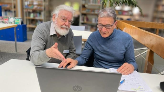 Digitalmentoren in der Stadtbücherei Zwei Männer sitzen an einem Tisch in einer Beratungssituation