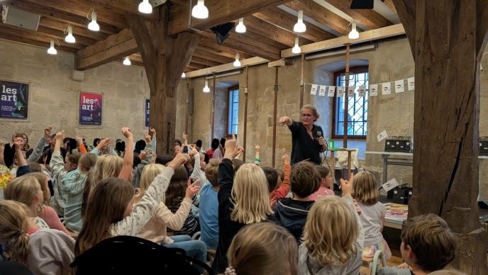 Abschlussveranstaltung Heiss auf Lesen 2025 Lesung / Interaktion mit Autorin auf Bühne und vielen Kindern als Zuschauen, die sich melden