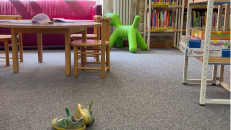 Kindertisch, Stühle, rotes Sofa neben Bücherregal in der Kinderbüchererei